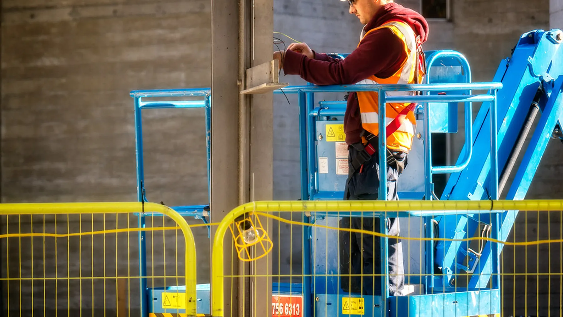 Electrician in hi-vis working safely from an elevated platform