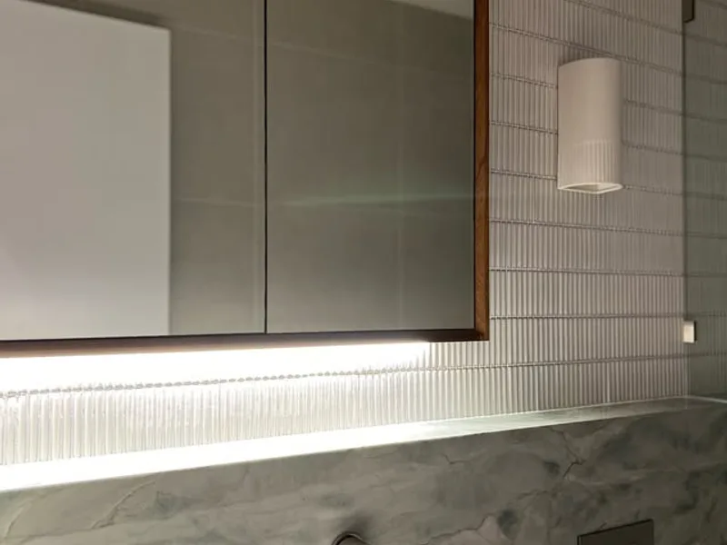 Backlit mirror cabinet and wall light in a bathroom